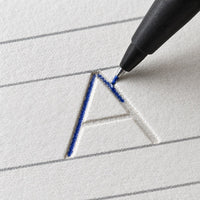 Macro d'une lettre creusée dans la page et du stylo