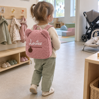 Petite fille qui arrive à la crèche avec son sac à dos ourson