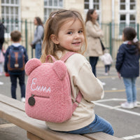 Petite fille assise dans la cour avec son sac ourson rose Emma - Rose